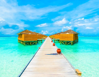 Wooden boardwalk leading to overwater bungalows on turquoise sea