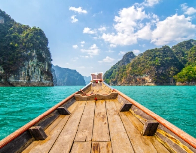 Boat bow facing turquoise water with green limestone cliffs